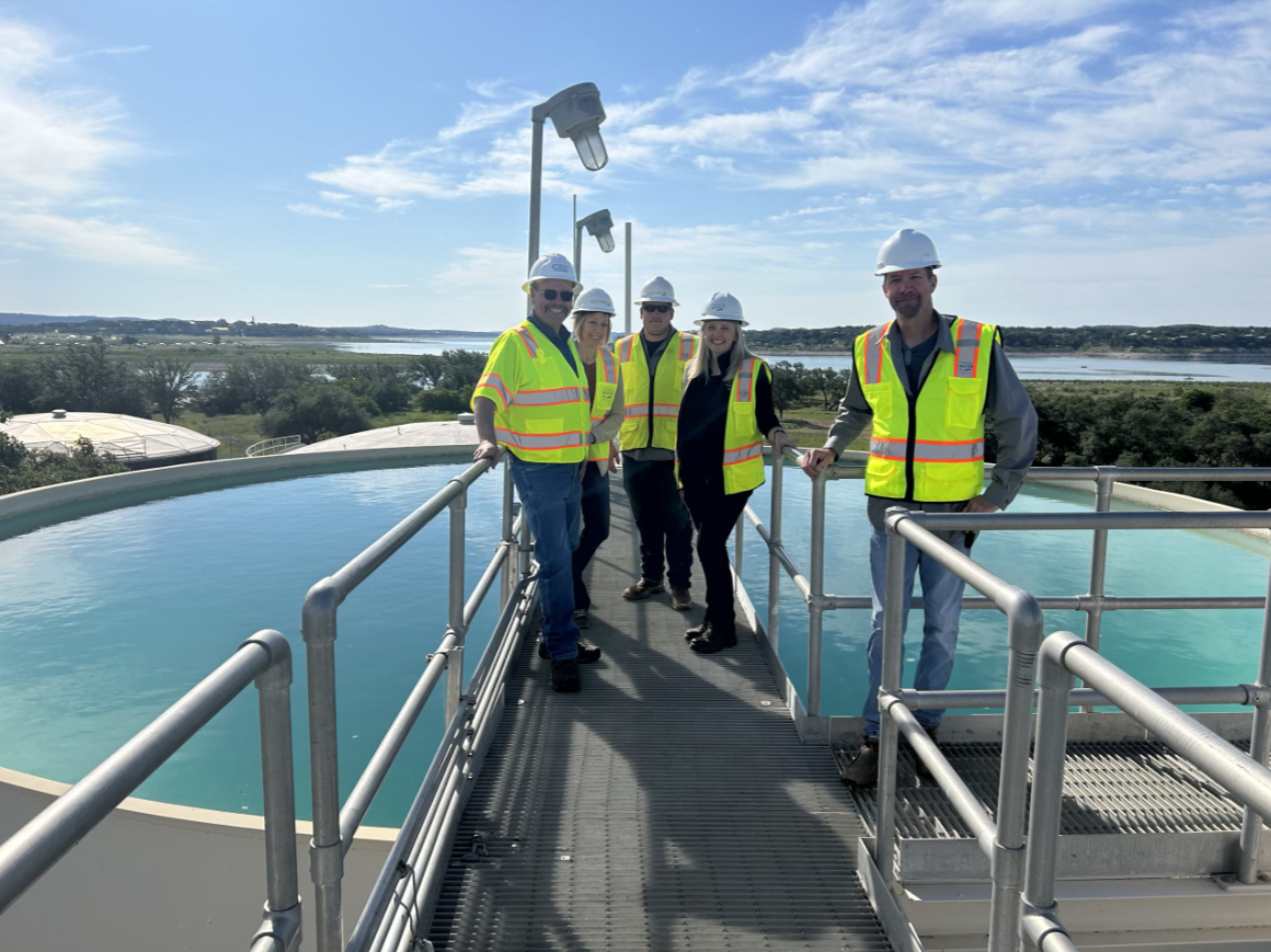 employees with safety vests and hard hats around a water tank